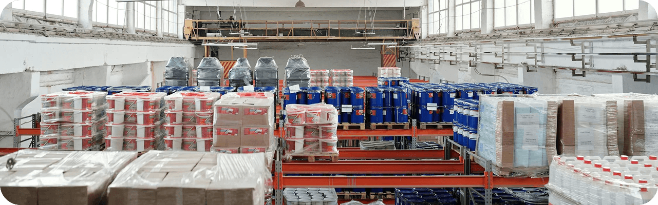 A large industrial warehouse floor filled with pallets stacked high with various packaged products.
